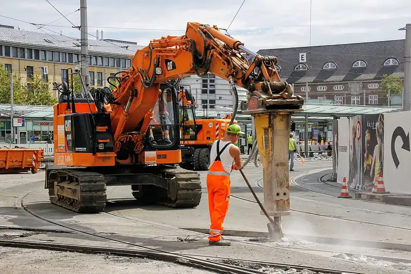 Eine Baustelle am Straßenbahnnetz in Bremen.  Zu sehen sind große Maschinen und im Vordergrund ein Arbeiter.