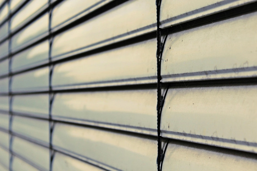A close-up of a closed roller blind shading a window from the outside.