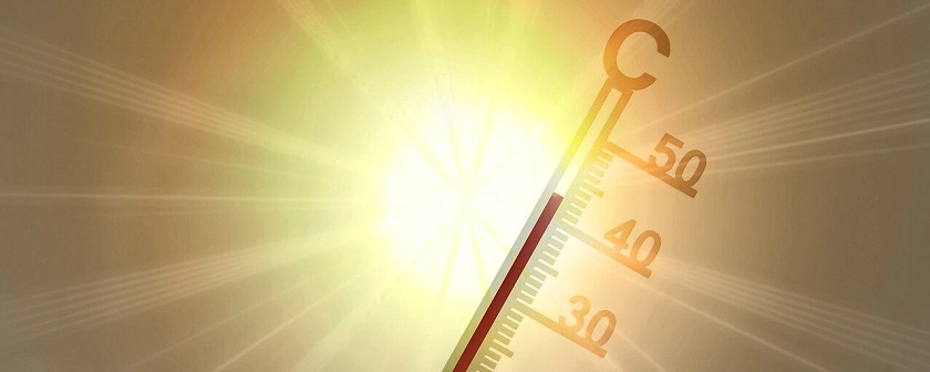 Ein Quarzthermometer, welches über 40 Grad Celsius anzeigt. Im Hintergrund ist eine stark scheinende Sonne.