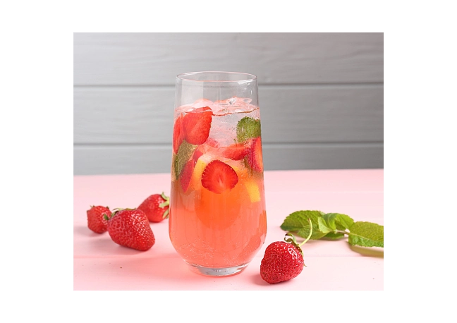 Glas mit Fruchtschorle, Erdbeerstücken und Minzblättern
